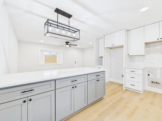 kitchen with hanging light fixtures, light wood-style floors, white cabinetry, and light countertops