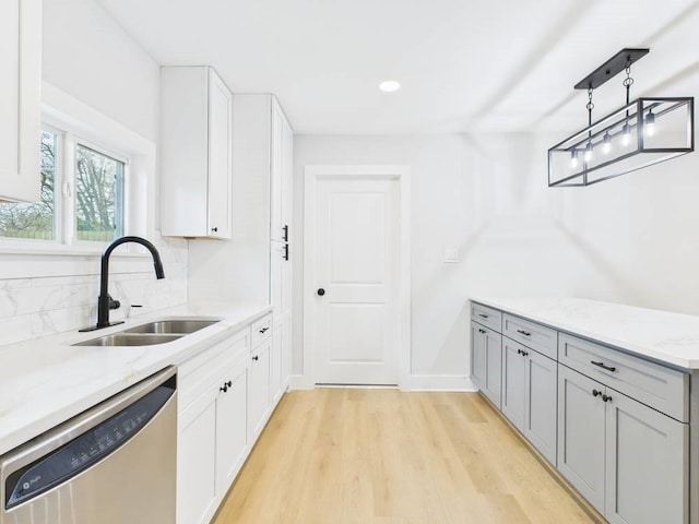 kitchen with light stone counters, light wood-style flooring, a sink, white cabinetry, and dishwasher