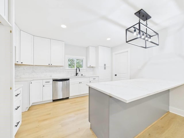 kitchen featuring light wood-style flooring, a peninsula, light stone countertops, stainless steel dishwasher, and a sink