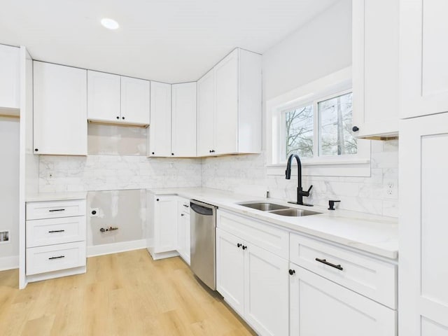 kitchen with white cabinets, a sink, backsplash, and stainless steel dishwasher