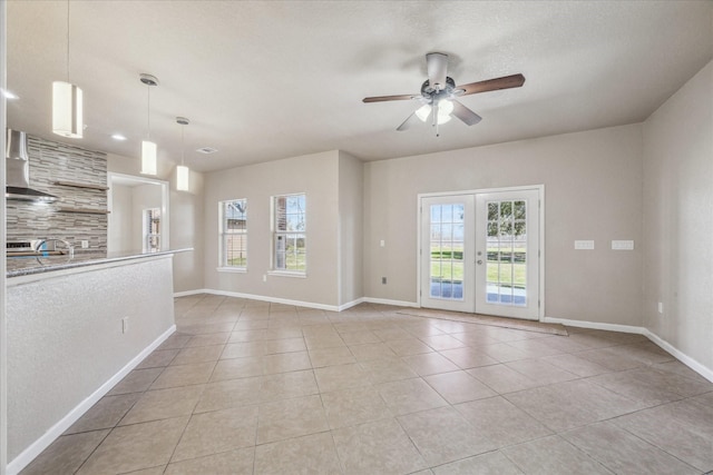 unfurnished room with light tile patterned floors, french doors, a wealth of natural light, and baseboards