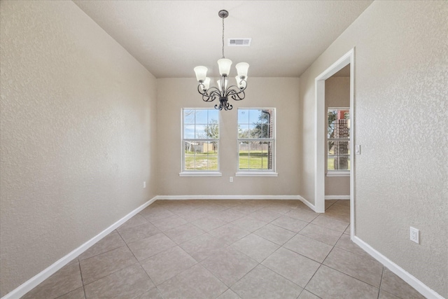 unfurnished dining area with a chandelier, visible vents, a textured wall, and baseboards