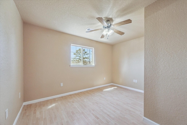 unfurnished room featuring a textured ceiling, wood finished floors, a ceiling fan, and baseboards