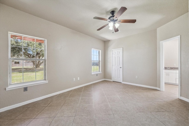 empty room featuring ceiling fan, baseboards, and light tile patterned floors