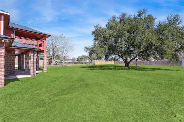 view of yard with fence and a balcony