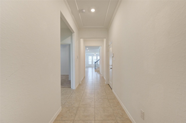 hall featuring light tile patterned floors, ornamental molding, and baseboards