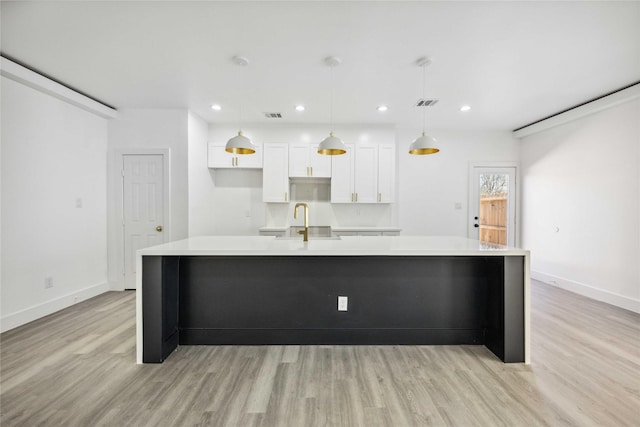 kitchen featuring visible vents, light wood finished floors, a large island, and white cabinetry