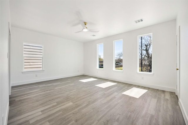 unfurnished room with light wood-type flooring, visible vents, baseboards, and ceiling fan