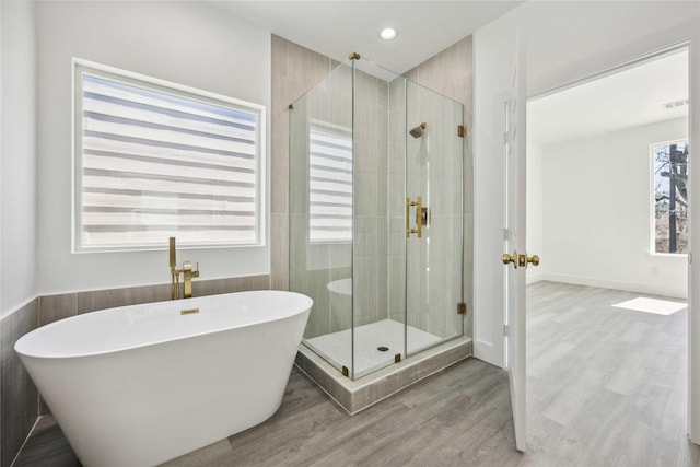 full bathroom with visible vents, a freestanding tub, wood finished floors, and a stall shower