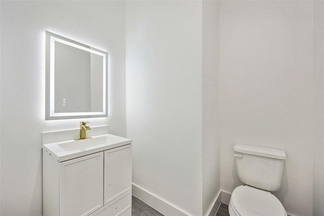 bathroom with baseboards, toilet, and vanity