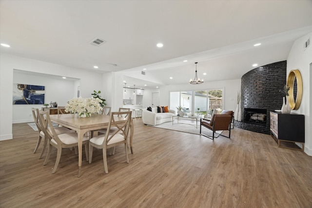 dining room featuring a notable chandelier, recessed lighting, visible vents, light wood-type flooring, and a brick fireplace