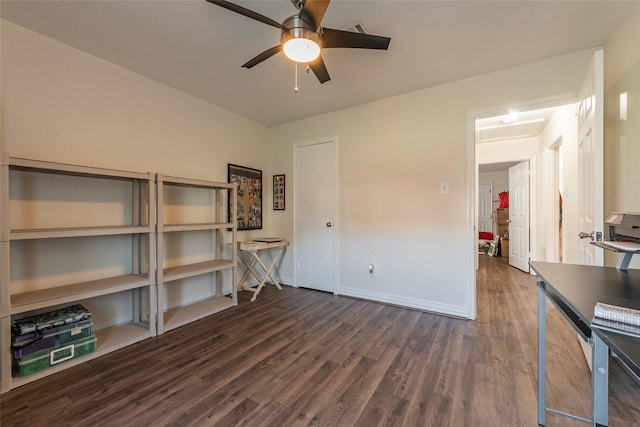 interior space with dark wood-type flooring, a ceiling fan, attic access, and baseboards