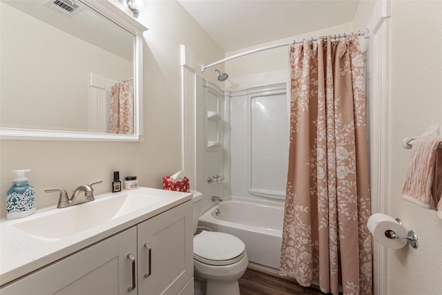 bathroom with toilet, wood finished floors, vanity, visible vents, and shower / tub combo with curtain