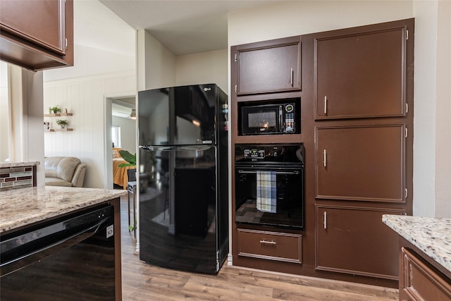 kitchen with black appliances, light wood finished floors, light stone counters, and dark brown cabinets