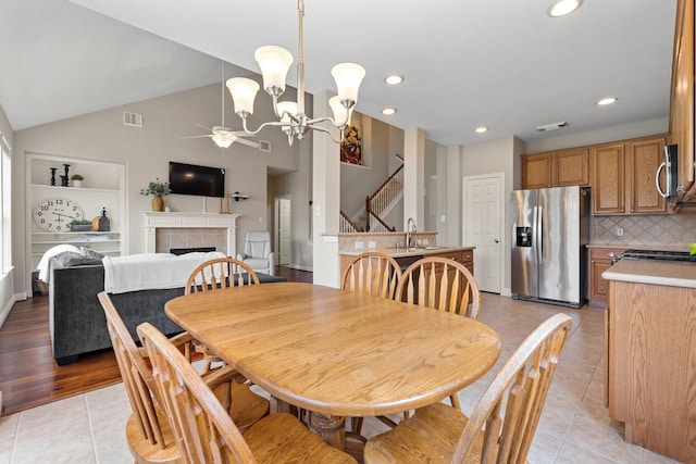 dining area with light tile patterned flooring, visible vents, a fireplace, and stairs