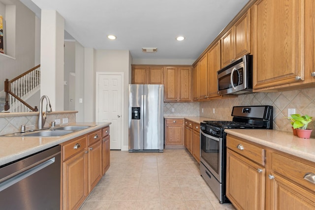 kitchen featuring light tile patterned floors, brown cabinets, stainless steel appliances, light countertops, and a sink