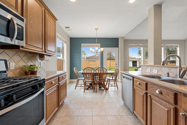 kitchen featuring stainless steel appliances, brown cabinetry, light countertops, and a sink