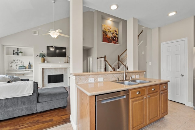 kitchen with a kitchen island with sink, a sink, open floor plan, light countertops, and stainless steel dishwasher