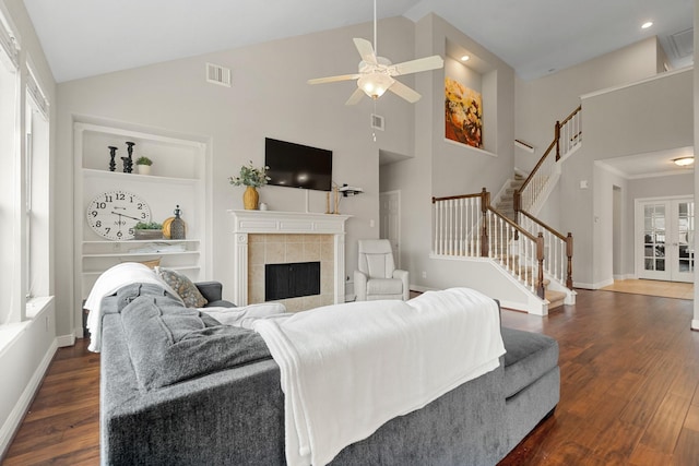 living area featuring stairway, dark wood-style floors, built in features, and a tile fireplace