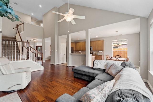 living room featuring baseboards, dark wood finished floors, stairs, ceiling fan with notable chandelier, and recessed lighting