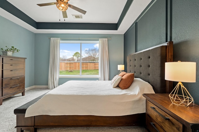 bedroom with visible vents, baseboards, a raised ceiling, ceiling fan, and carpet