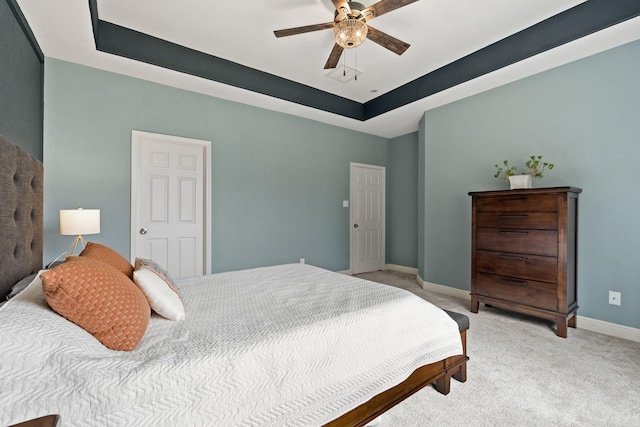 bedroom with light carpet, ceiling fan, baseboards, and a raised ceiling