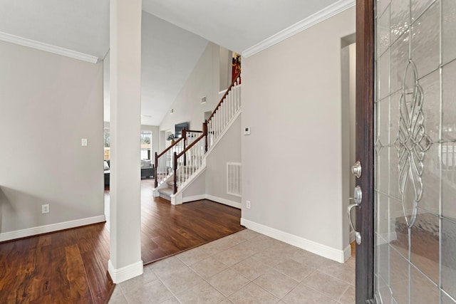 foyer featuring light tile patterned floors, baseboards, visible vents, stairway, and crown molding