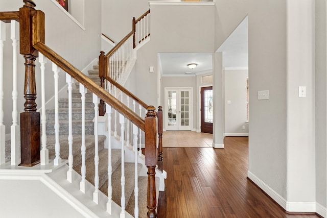 entryway featuring crown molding, a high ceiling, baseboards, and wood finished floors