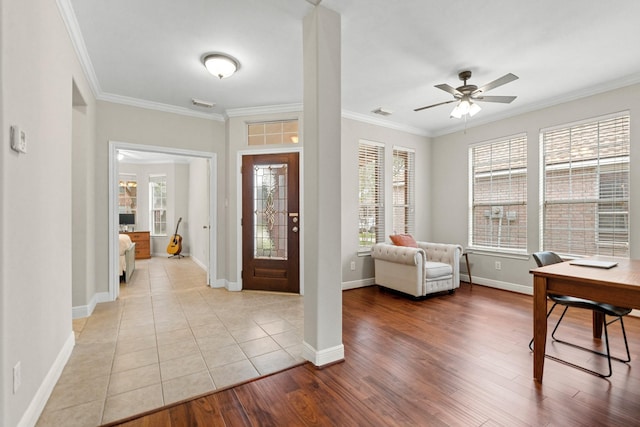 foyer featuring ceiling fan, light wood-style flooring, visible vents, baseboards, and ornamental molding