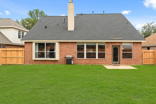 rear view of house featuring a chimney, a patio area, fence, and a lawn