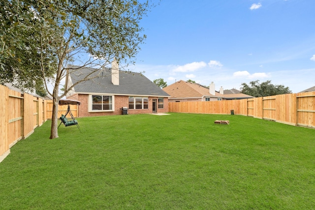 back of property with a fenced backyard, a chimney, and a yard