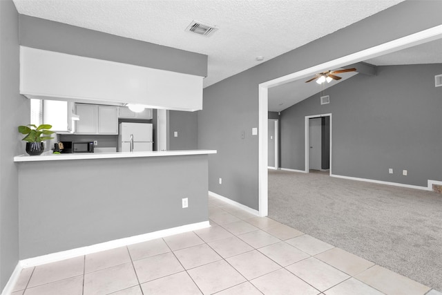 kitchen with a peninsula, visible vents, white cabinets, light countertops, and freestanding refrigerator