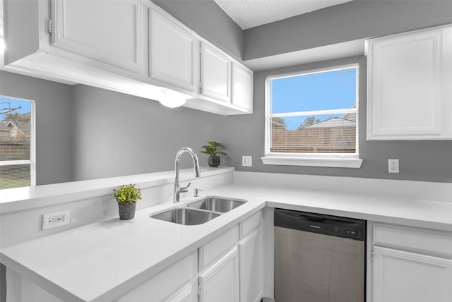 kitchen with white cabinets, a peninsula, light countertops, stainless steel dishwasher, and a sink