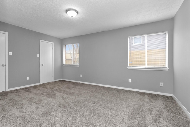 unfurnished room with carpet, a textured ceiling, and baseboards