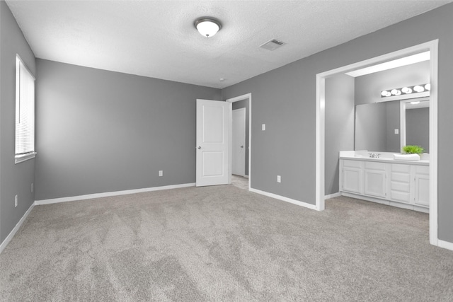 11330 Sunfish Ln, Houston, TX 77067 - unfurnished bedroom featuring carpet floors, baseboards, a textured ceiling, a sink, and connected bathroom