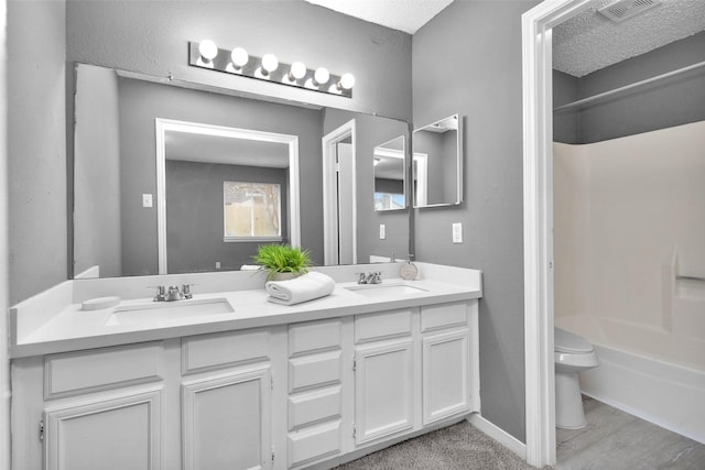 full bath featuring visible vents, double vanity, a sink, and toilet