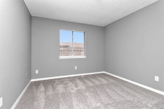 unfurnished room with a textured ceiling, carpet floors, and baseboards