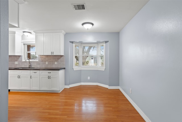 11707 Bowie Dr, La Porte, TX 77571 - kitchen featuring dark countertops, a sink, visible vents, and white cabinets