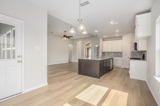 411 Wellshire Dr, West Columbia, TX 77486 - kitchen with open floor plan, tasteful backsplash, light wood-style flooring, an island with sink, and white cabinetry