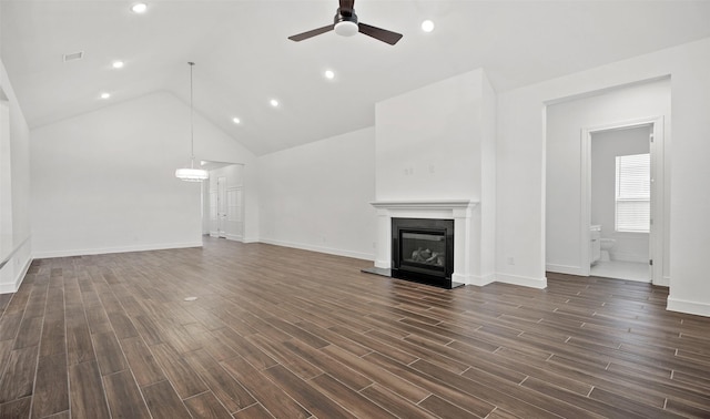 128 Luther Dean Ln, New Waverly, TX 77358 - unfurnished living room featuring a ceiling fan, a glass covered fireplace, vaulted ceiling, dark wood-type flooring, and baseboards