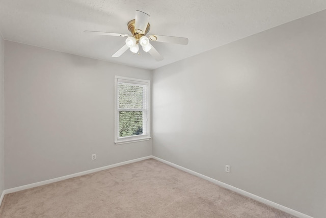 empty room featuring light carpet, ceiling fan, and baseboards