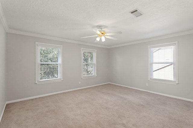 empty room with a textured ceiling, ornamental molding, light carpet, and baseboards