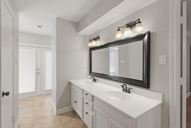 full bathroom featuring double vanity, french doors, a sink, and baseboards