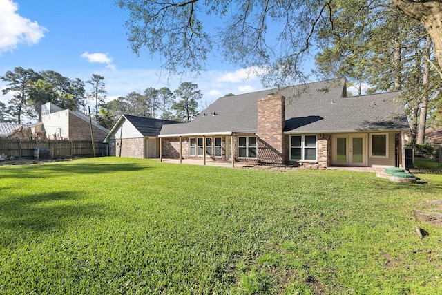 rear view of house featuring french doors, a yard, a chimney, a patio area, and fence