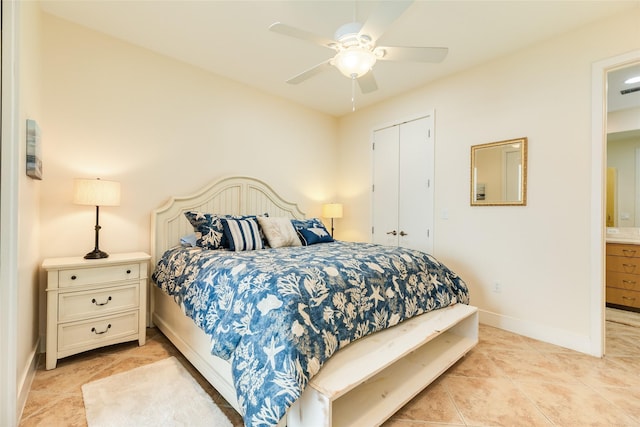bedroom with light tile patterned flooring, ceiling fan, ensuite bath, and baseboards