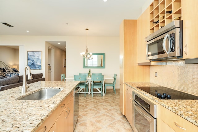 kitchen featuring appliances with stainless steel finishes, hanging light fixtures, a sink, and light brown cabinetry