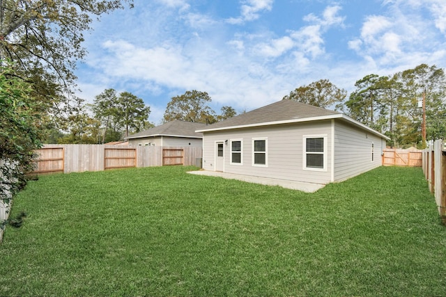 back of house with a fenced backyard and a lawn