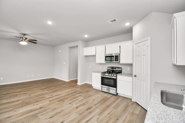 kitchen featuring visible vents, white cabinetry, stainless steel appliances, and light stone counters