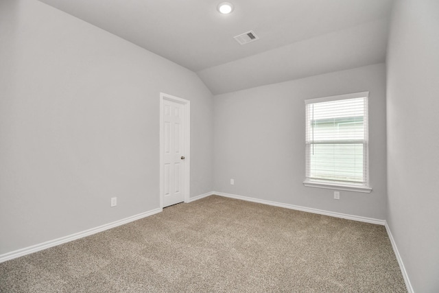 empty room with carpet floors, lofted ceiling, visible vents, and baseboards