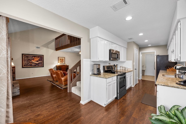 kitchen featuring appliances with stainless steel finishes, white cabinetry, visible vents, and light stone counters